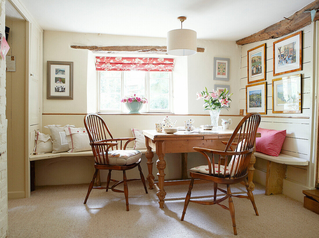 Lilies on wooden table with chairs at sunlit window of Devonshire cottage UK
