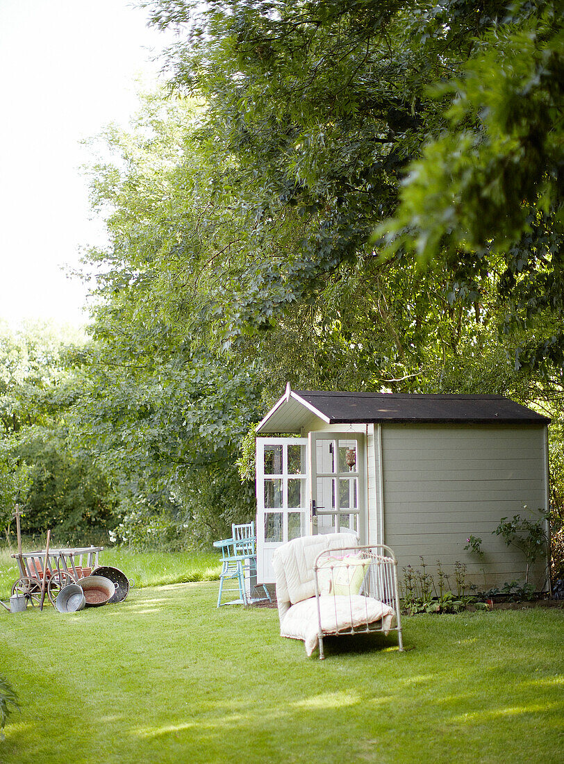 White shed and daybed on lawn in Devonshire garden UK