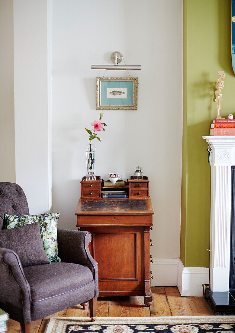 Polstersessel mit Vintage-Schreibkommode im Wohnzimmer eines Hauses in Kent, England UK