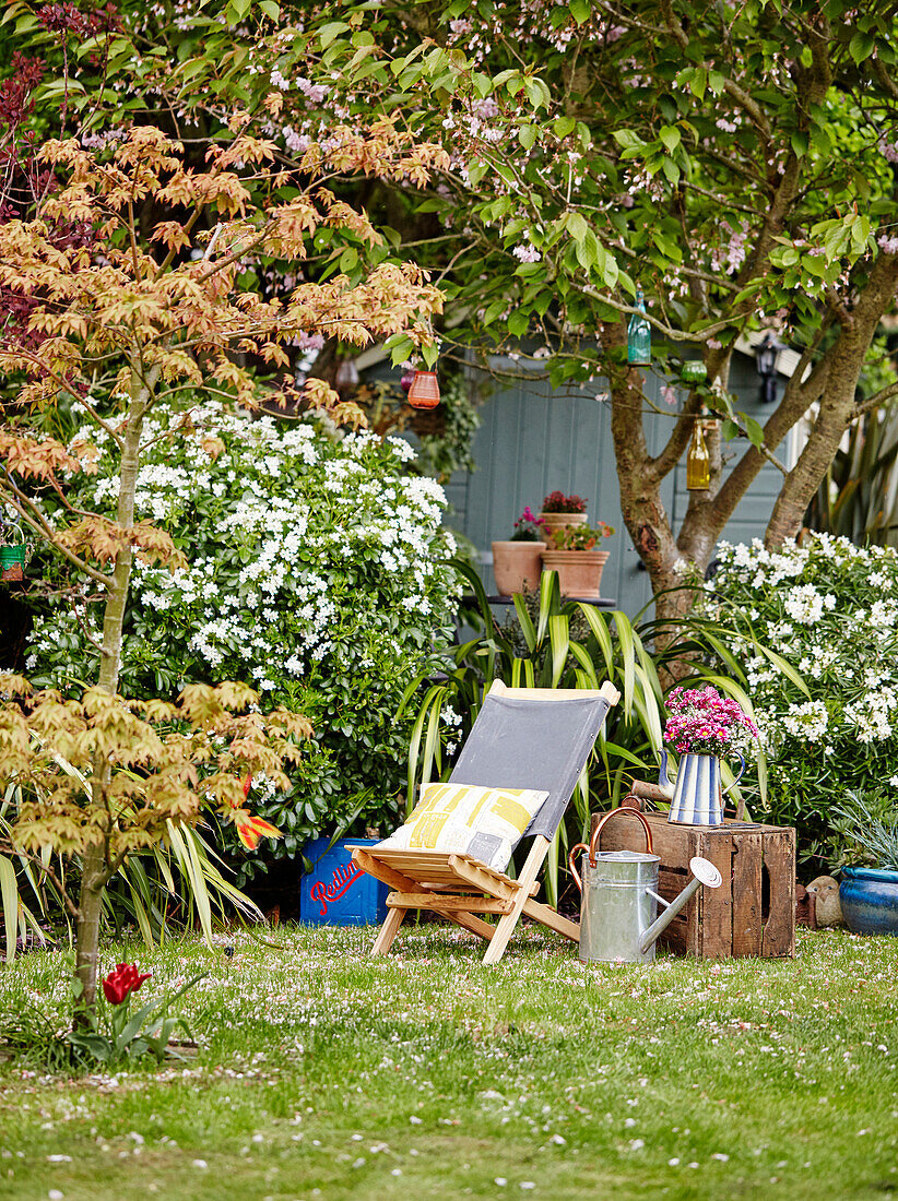Liegestuhl und Gießkanne im Garten eines Hauses in Kent, England, UK