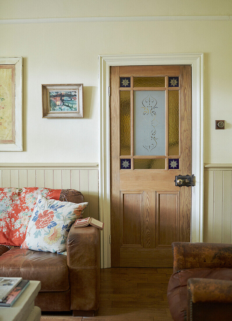 Braunes Ledersofa und Sessel mit Holz- und Buntglastür in Whitley Bay cottage Tyne and Wear England UK