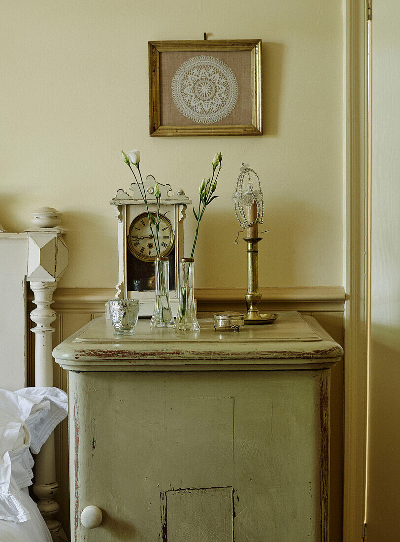 Single stem flowers and clock on bedside cabinet in Whitley Bay cottage Tyne and Wear England UK