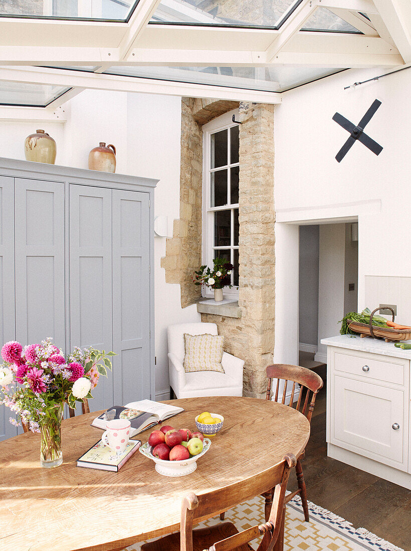 Freiliegende Steinmauer mit Fensterdetail in einer Küche in Bicester mit ovalem Holztisch Oxfordshire England