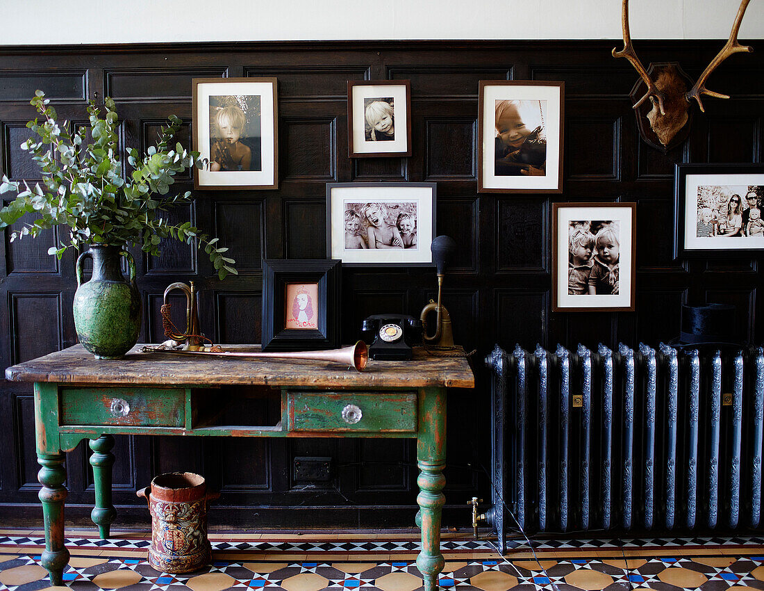 Original Victorian tiling and wooden paneling creates a grand entrance hall where family photographs and antiques including vintage horns and an old artillery shell carrier with a hand-painted royal coat of arms