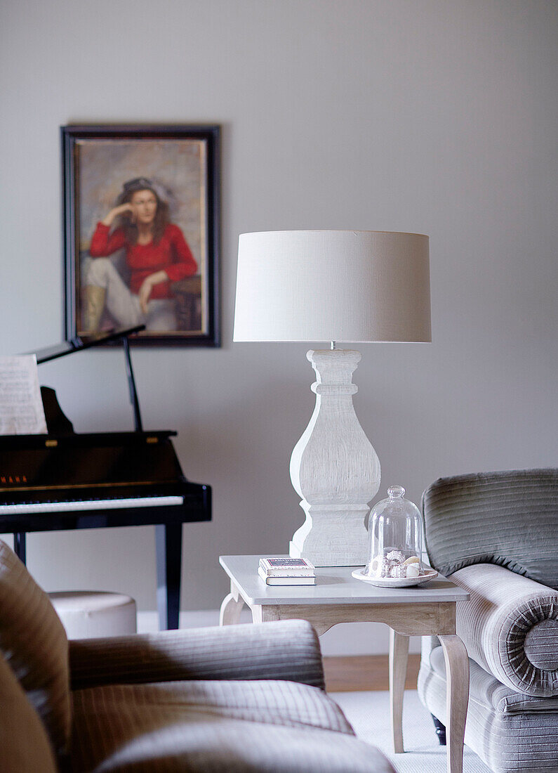 Cream lamp on side table with piano and framed portrait in Buckinghamshire home UK