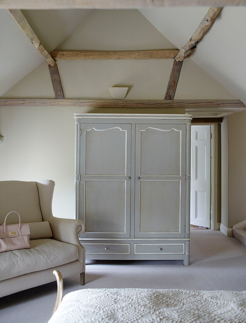 Hellgrauer Kleiderschrank und Sofa in einem Schlafzimmer mit Balken in Buckinghamshire UK