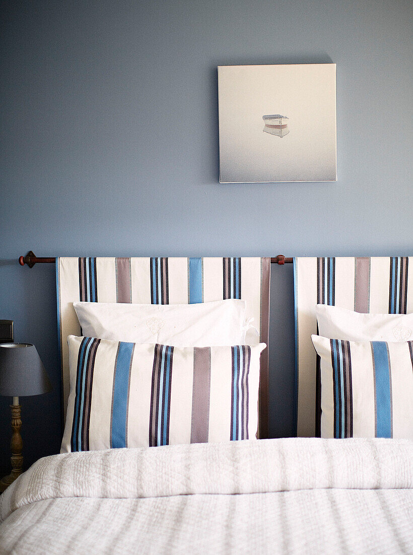 Kombiniertes Kopfteil mit gestreiften Kissen im hellblauen Schlafzimmer eines Gästehauses in der Bretagne, Frankreich