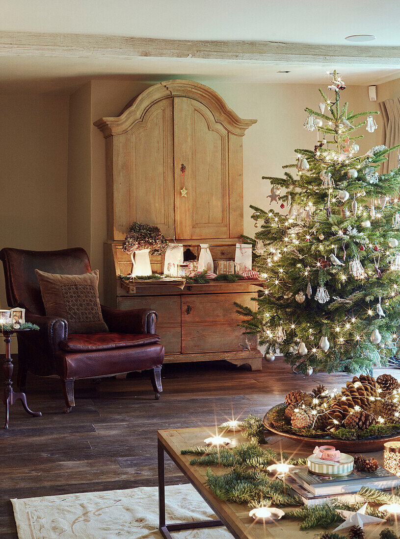 Weihnachtsbaum mit Sessel und Kommode in einem Haus in Oxfordshire, England, UK