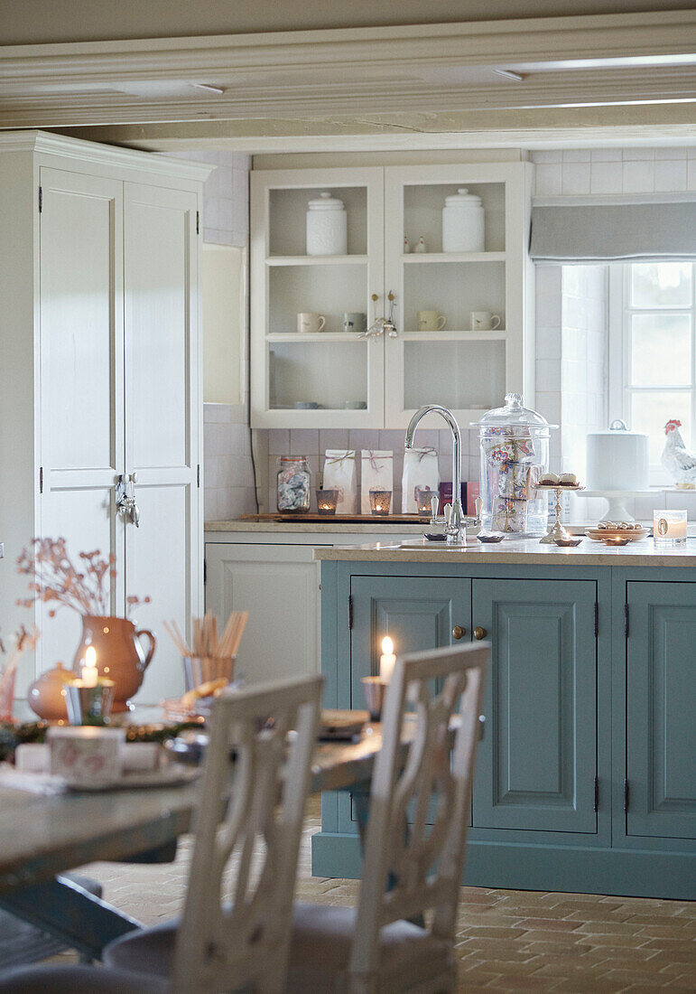 Nahaufnahme einer Wohnküche mit einem Esstisch mit Kerzenlicht und blau gestrichenen Schränken