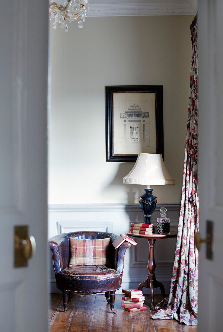 Lamp and books with antique leather chair in corner of County Durham home England UK