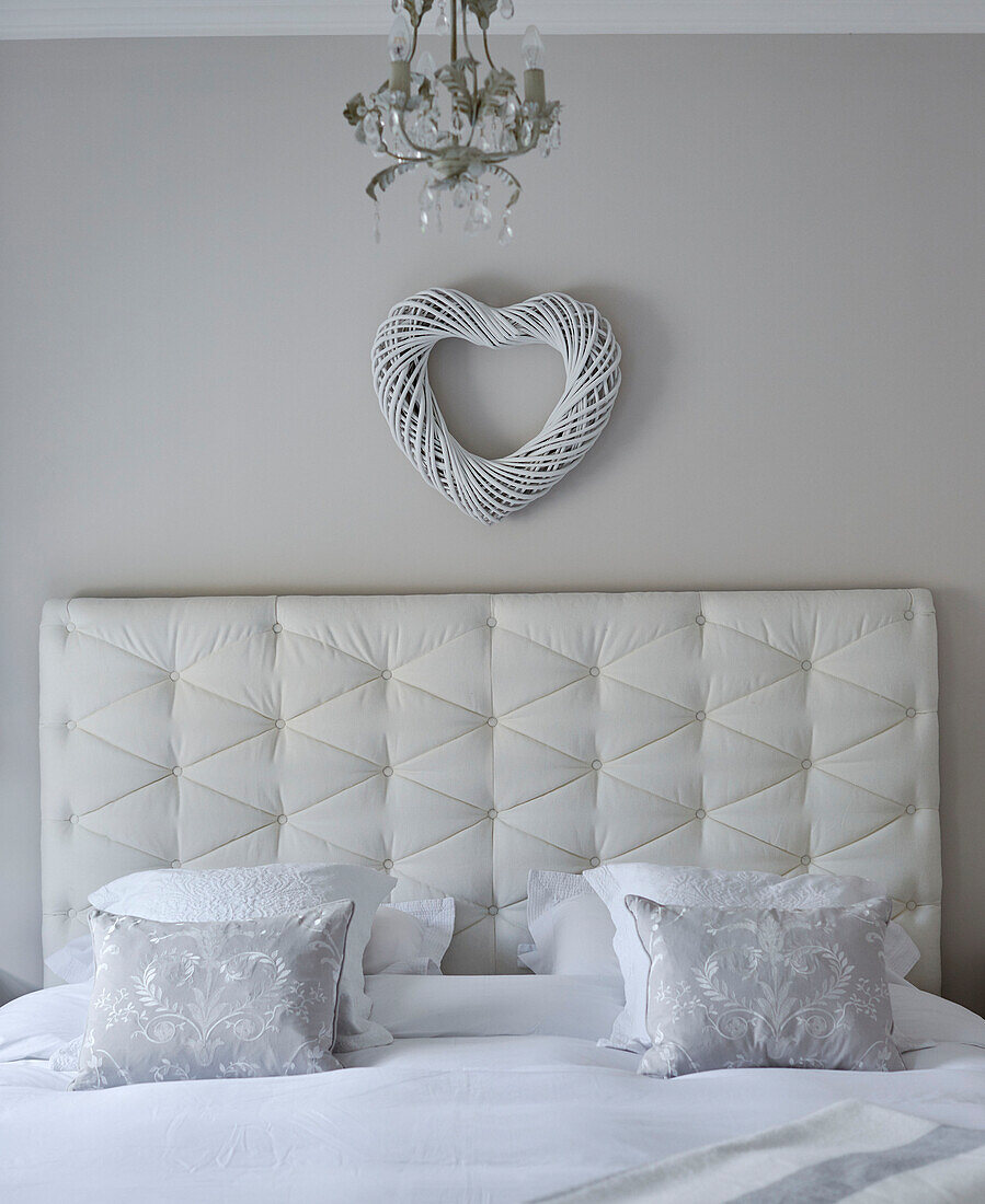 Heart above buttoned headboard with light grey pillows in York townhouse England UK