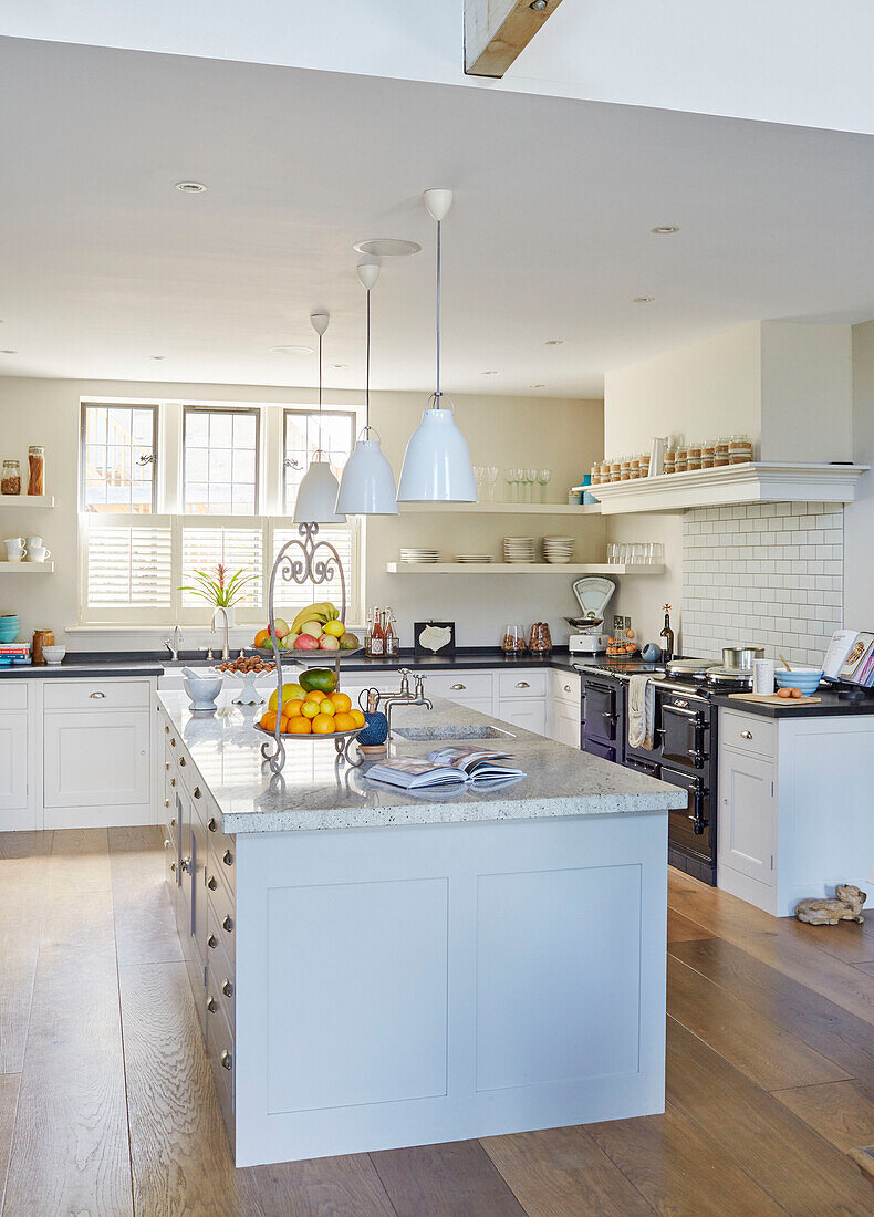White pendant lights hang above kitchen island in modernised Northumbrian country house UK