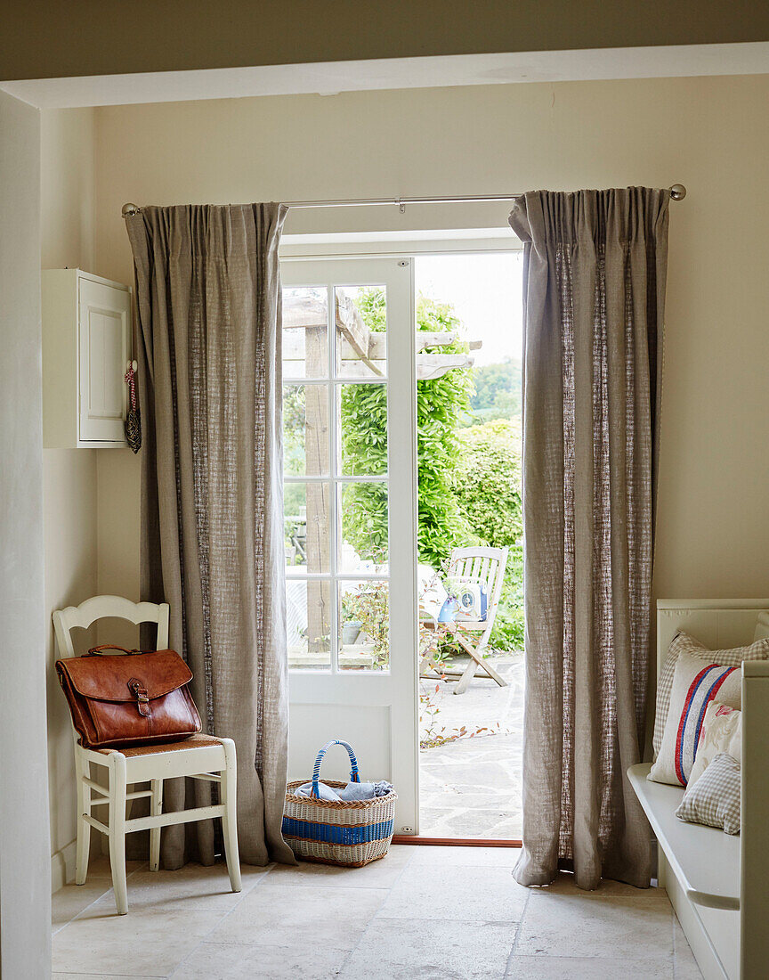 Braune Ledertasche auf einem Stuhl an einer offenen Tür zum Garten in einem Haus in Northumbria, England UK