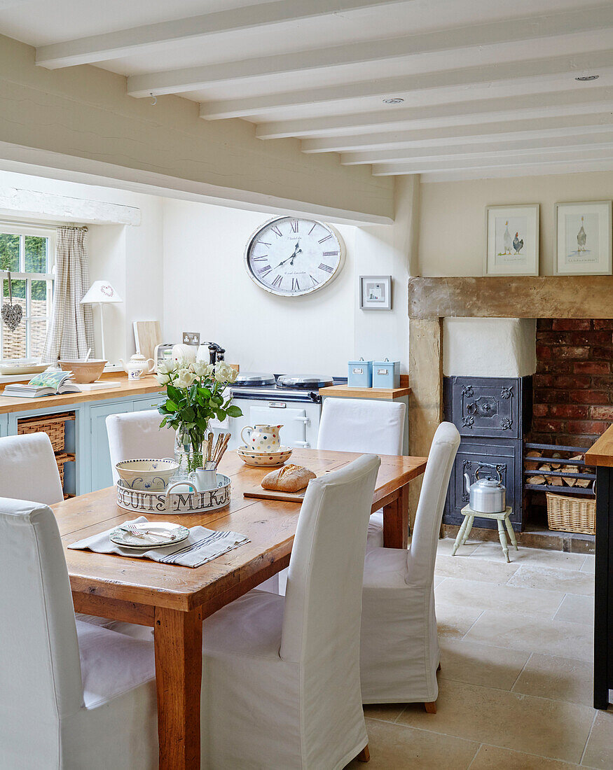 Wooden table with slip-cover dining chairs in open-plan kitchen of Northumbrian home England UK