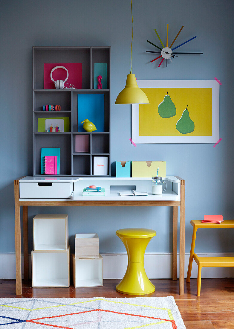 Yellow stool and pendant light at desk in light blue work studio, UK