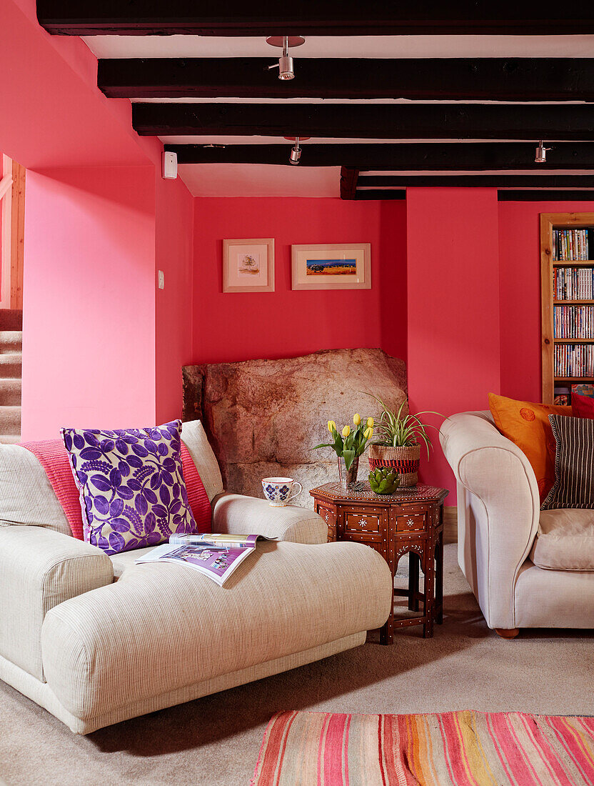 Breiter cremefarbener Sessel mit geschnitztem indischem Beistelltisch im rosa Wohnzimmer eines nordumbrischen Mühlenhauses aus dem 18