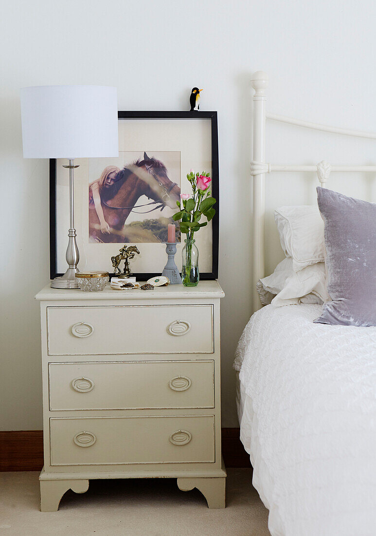 Cut flowers and riding memorabilia on painted bedside chest in Kent home, North East England, UK
