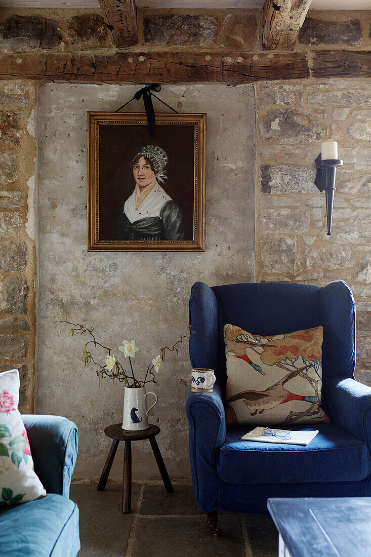 Blue wingback armchair below framed oil painting in Grade II listed Tudor bastle Northumberland UK