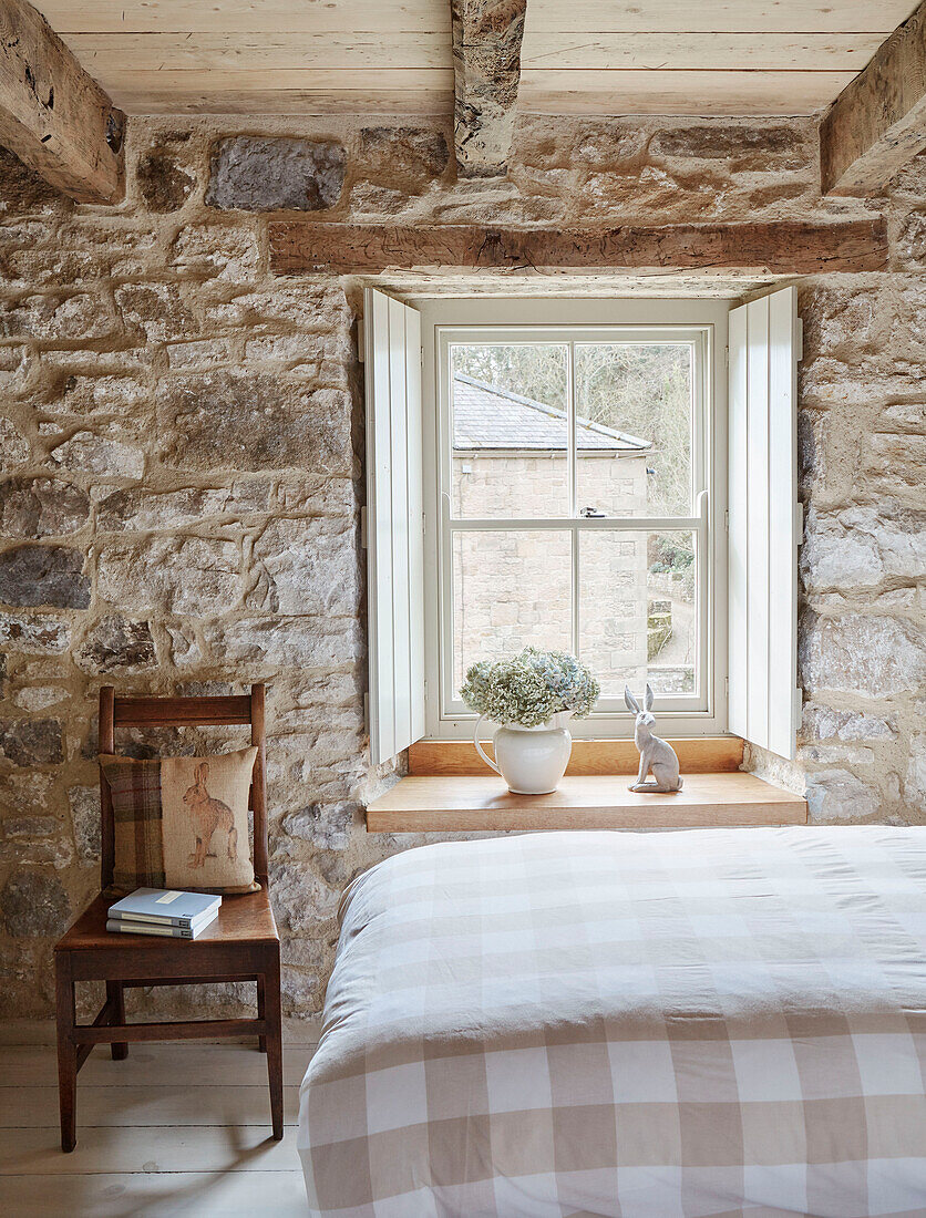 Holzstuhl am Fenster mit Fensterläden in einem Schlafzimmer aus Naturstein in einer unter Denkmalschutz stehenden Tudor-Bastle Northumberland UK