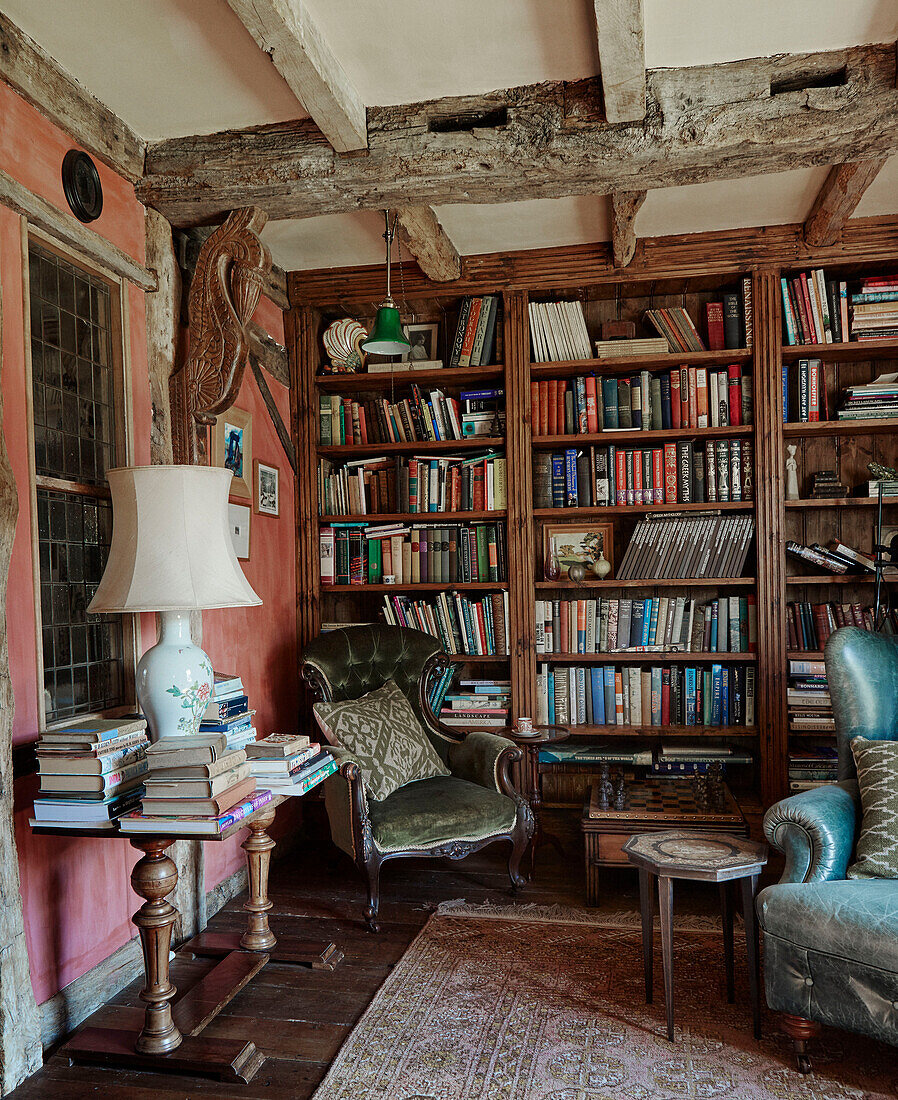 Green velvet armchair in corner of library in Herefordshire farmhouse, UK