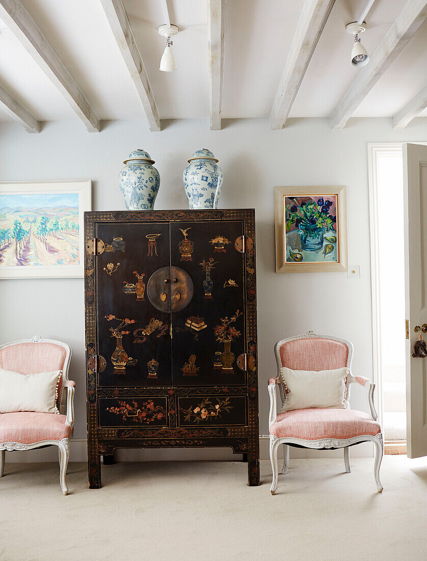 Pair of pink armchairs with Chines lacquered cabinet in Warwickshire farmhouse, UK