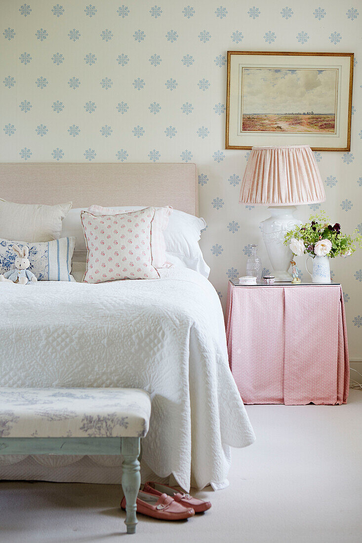 Weißer Bettbezug mit Nachttisch aus rosa Stoff in einem Bauernhaus in Warwickshire, UK
