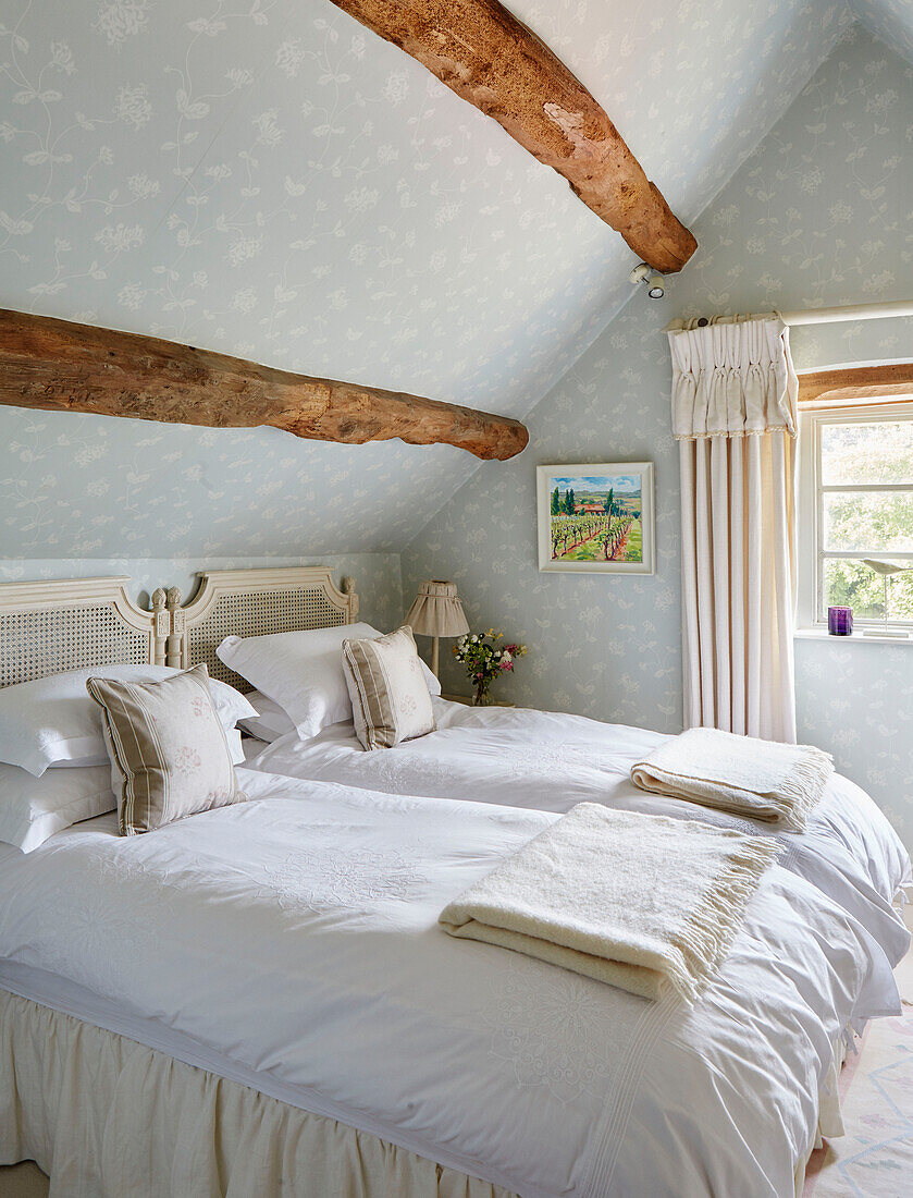 Twin beds with folded blankets in attic bedroom of Warwickshire farmhouse, UK