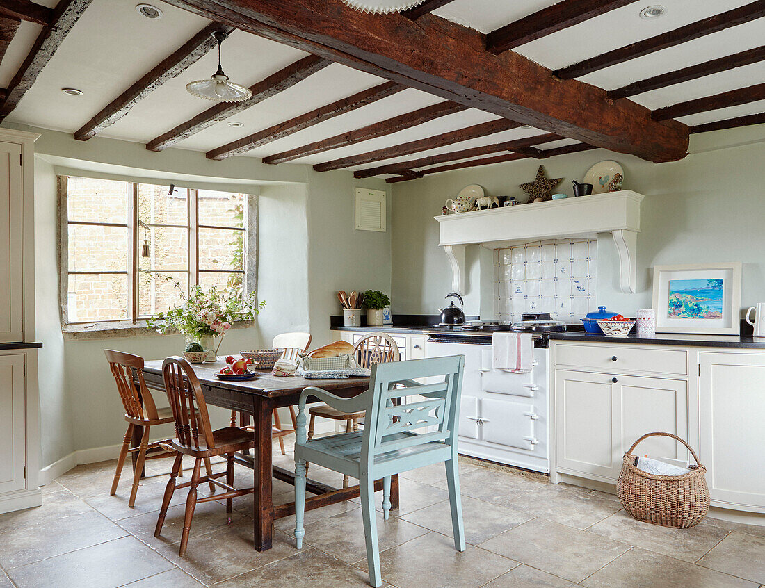 Küche mit Holzbalke, Tisch und Stühlen in einem Landhaus in Oxfordshire, England, UK