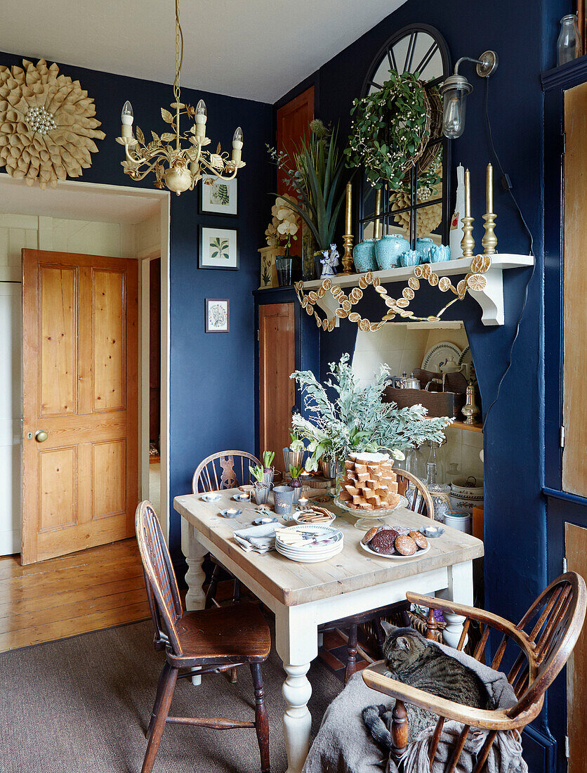 Vintage-Spiegel auf Regal über Tisch mit Fudge in blauer Küche ein einem Haus in Chippenham, Wiltshire, UK