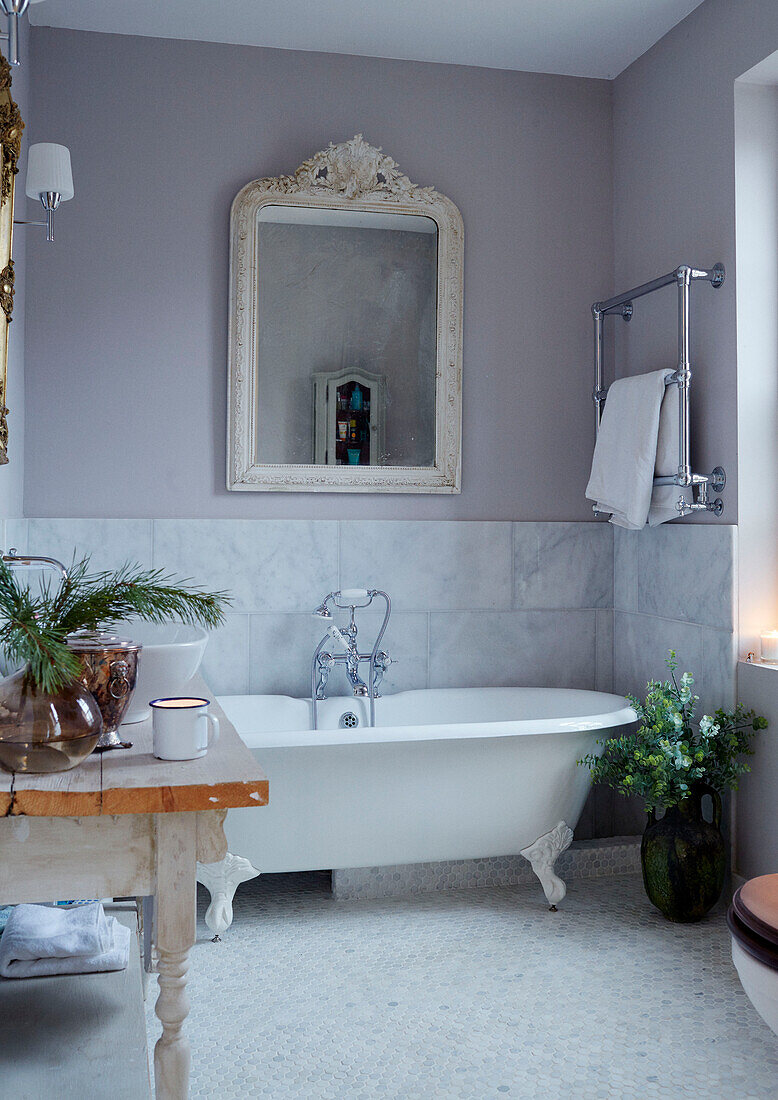 Freistehende Badewanne unter einem Spiegel mit Blattanordnung in einem Haus in East Grinstead, West Sussex, UK