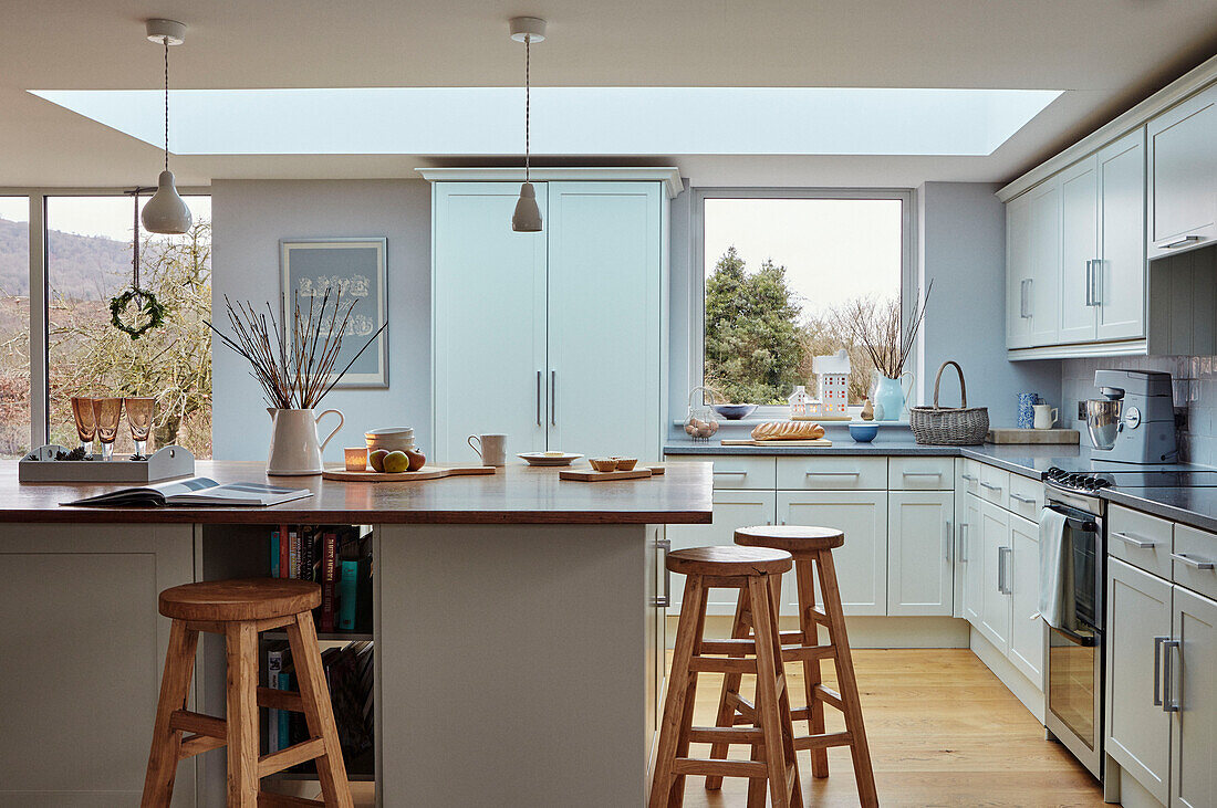 Barhocker aus Holz in einer modernen hellblauen Einbauküche in einem Haus in Worcestershire, England, UK