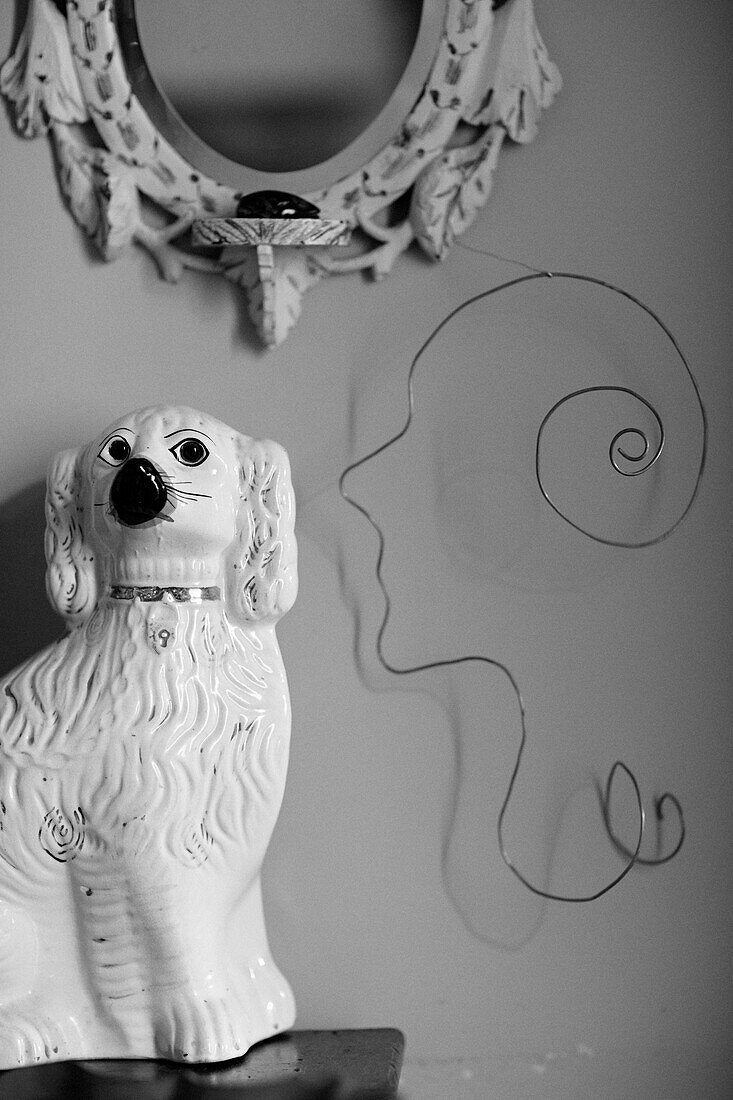 Hund aus Porzellan mit Gesichtsskulptur aus Draht und Spiegelrahmen in Powys Cottage, Wales, UK