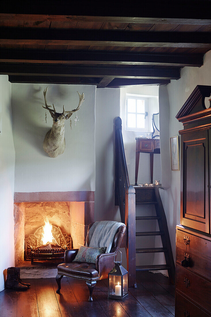 Ledersessel am beleuchteten Kamin in einem schottischen Schloss, UK