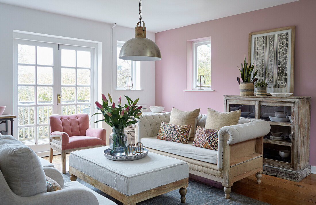 Geknöpftes Sofa und Sessel mit geschnittenen Lilien in rosa Wohnzimmer in einem Haus in Tunbridge Wells, Kent, UK
