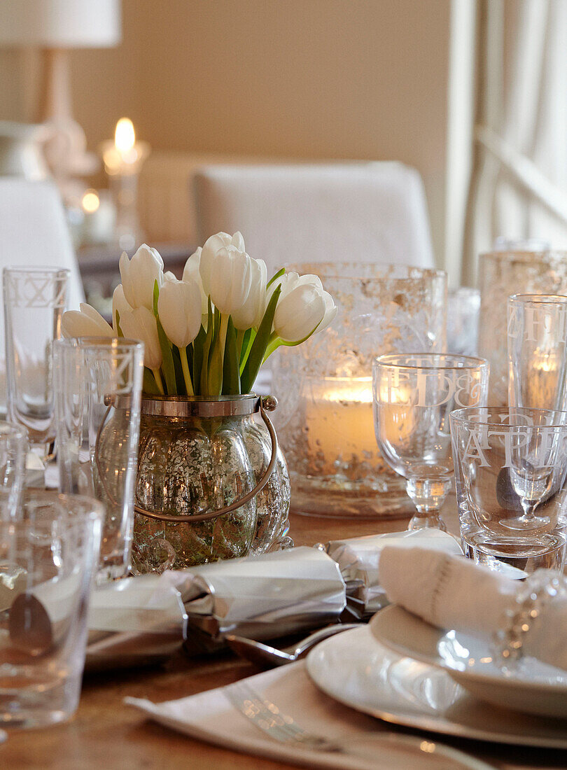 White tulips and vintage glassware on table set for Christmas dinner in, UK home