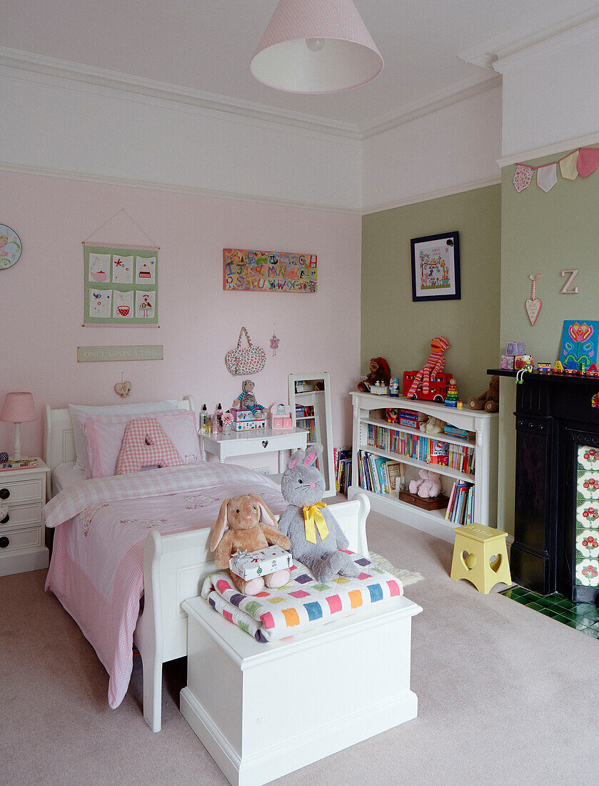Kuscheltiere auf einer Truhe mit Decke am Fußende des Bettes in einem Mädchenzimmer in einem britischen Haus