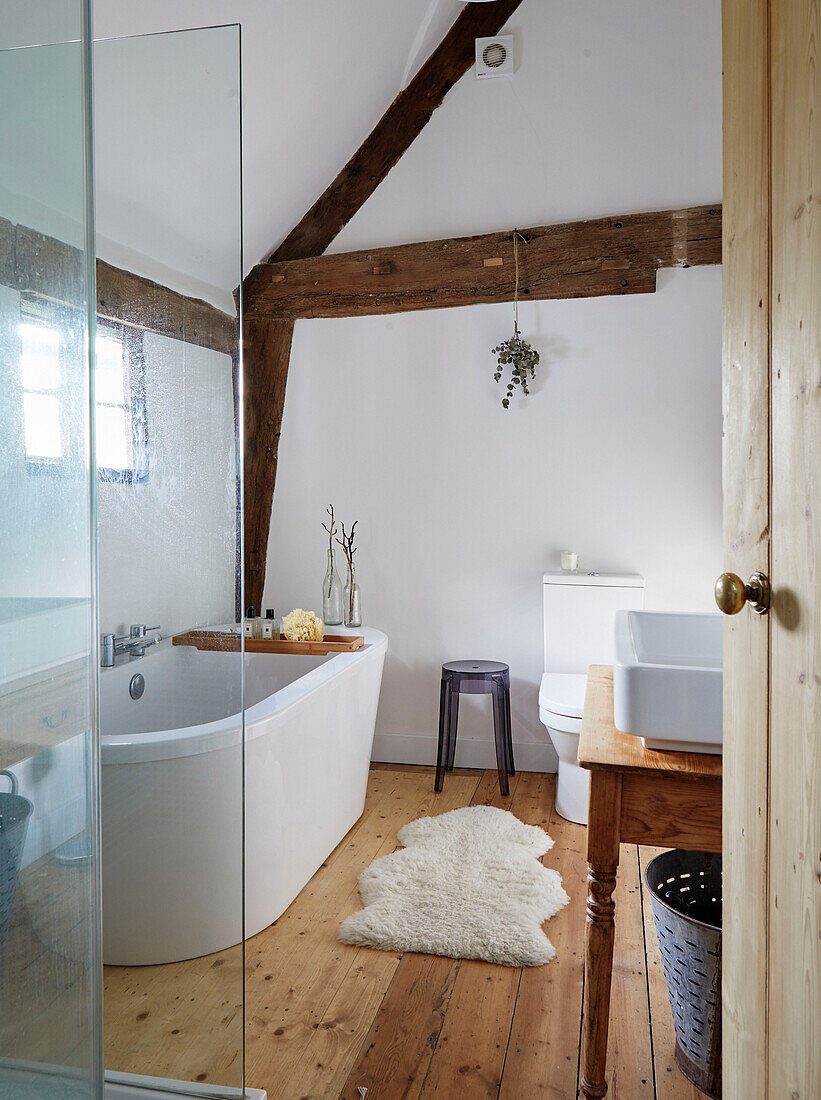 Freistehende Badewanne mit Vorleger und Duschkabine in einem Bauernhaus in Warwickshire, England, UK