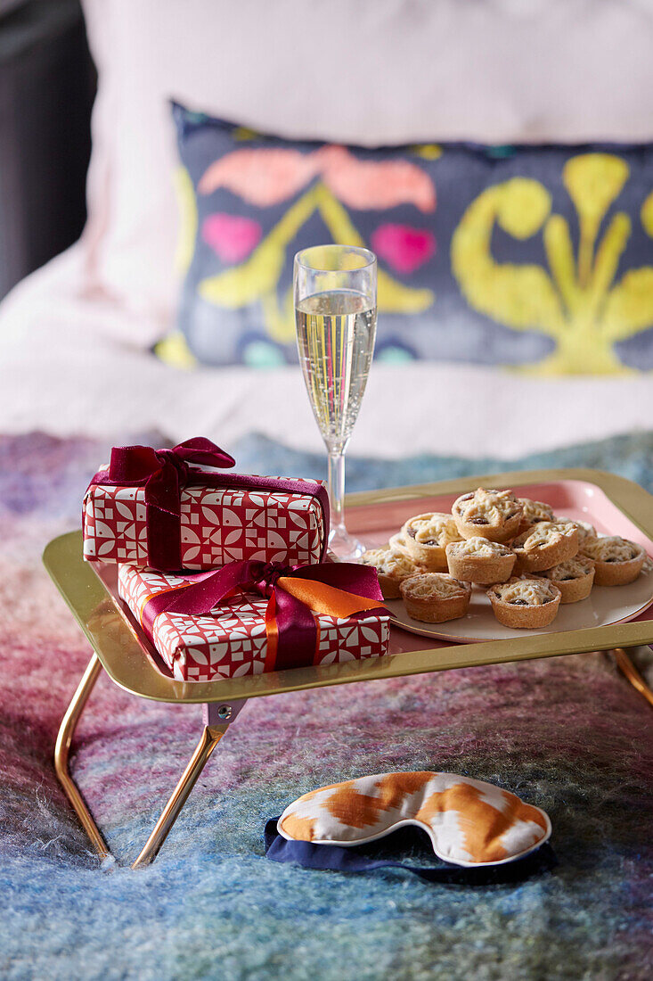 Champagne and mince pies with gift wrapped presents on breakfast tray in London home, UK