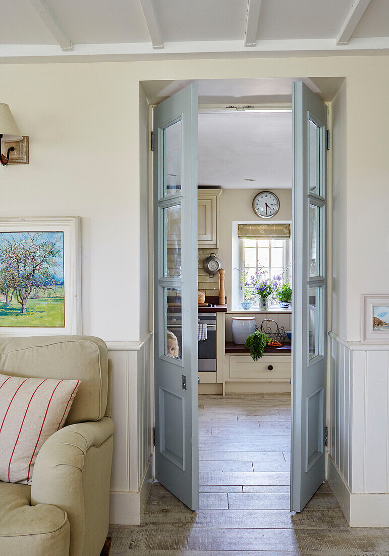 Blick durch Flügeltüren in die Küche von einem Cottage in Sandford St Martin, Oxfordshire, UK