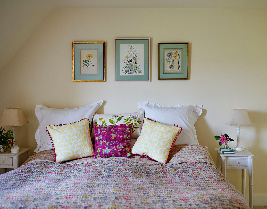 Botanical prints framed above double bed in Sandford St Martin cottage, Oxfordshire, UK