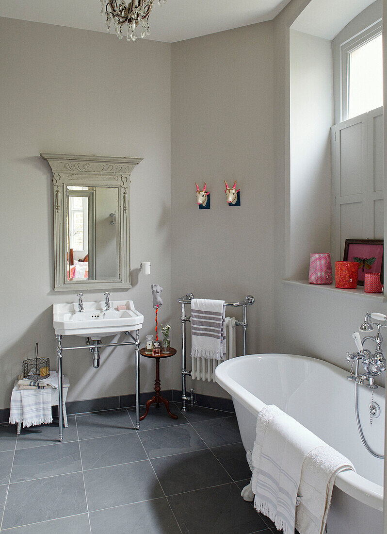 Freistehende Badewanne in einem grau gefliesten Badezimmer in einem Haus in Woodstock, Oxfordshire, UK