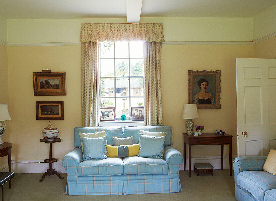 Hellblau kariertes Sofa am Fenster in einem Haus in Syresham, Northamptonshire, UK