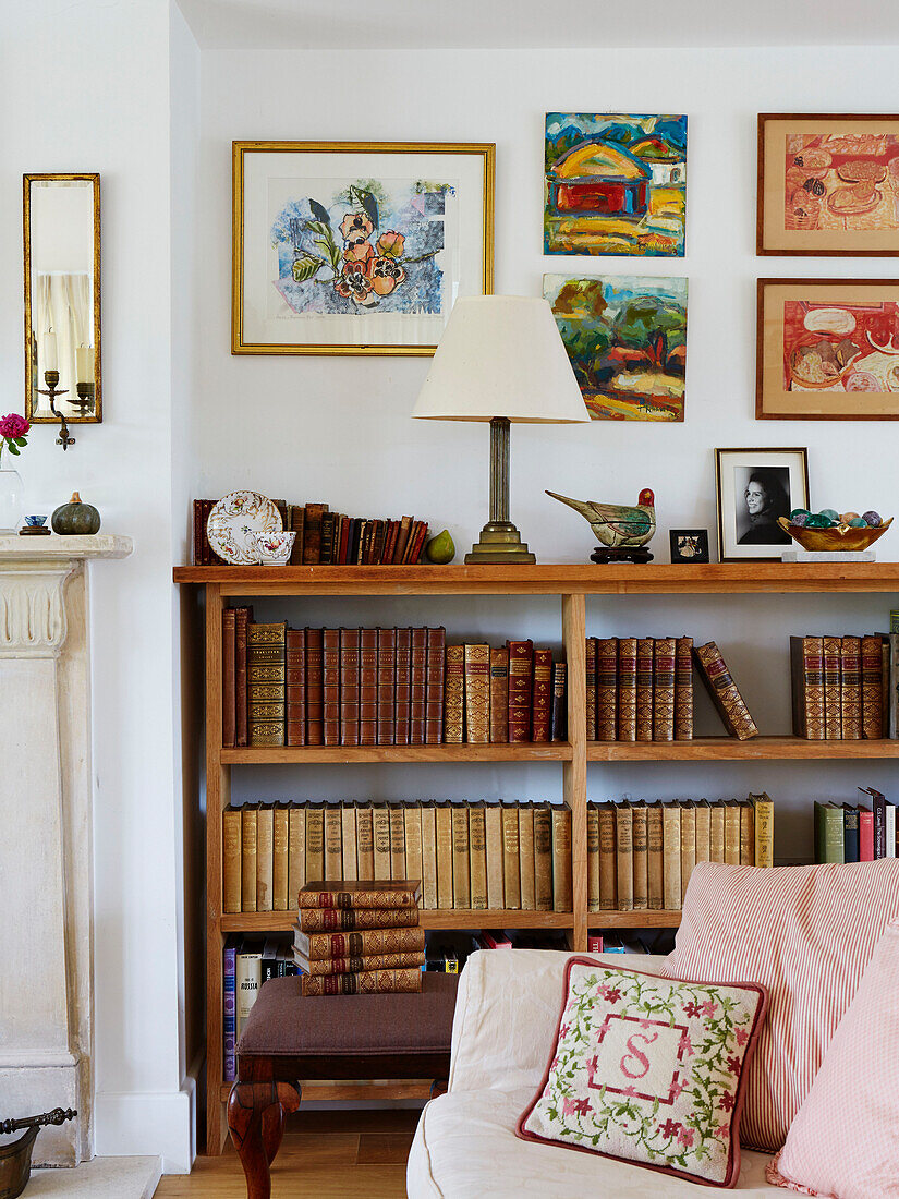 Gebundene Bücher auf Regalen mit gerahmter Kunst in einem Bauernhaus in Oxfordshire, UK