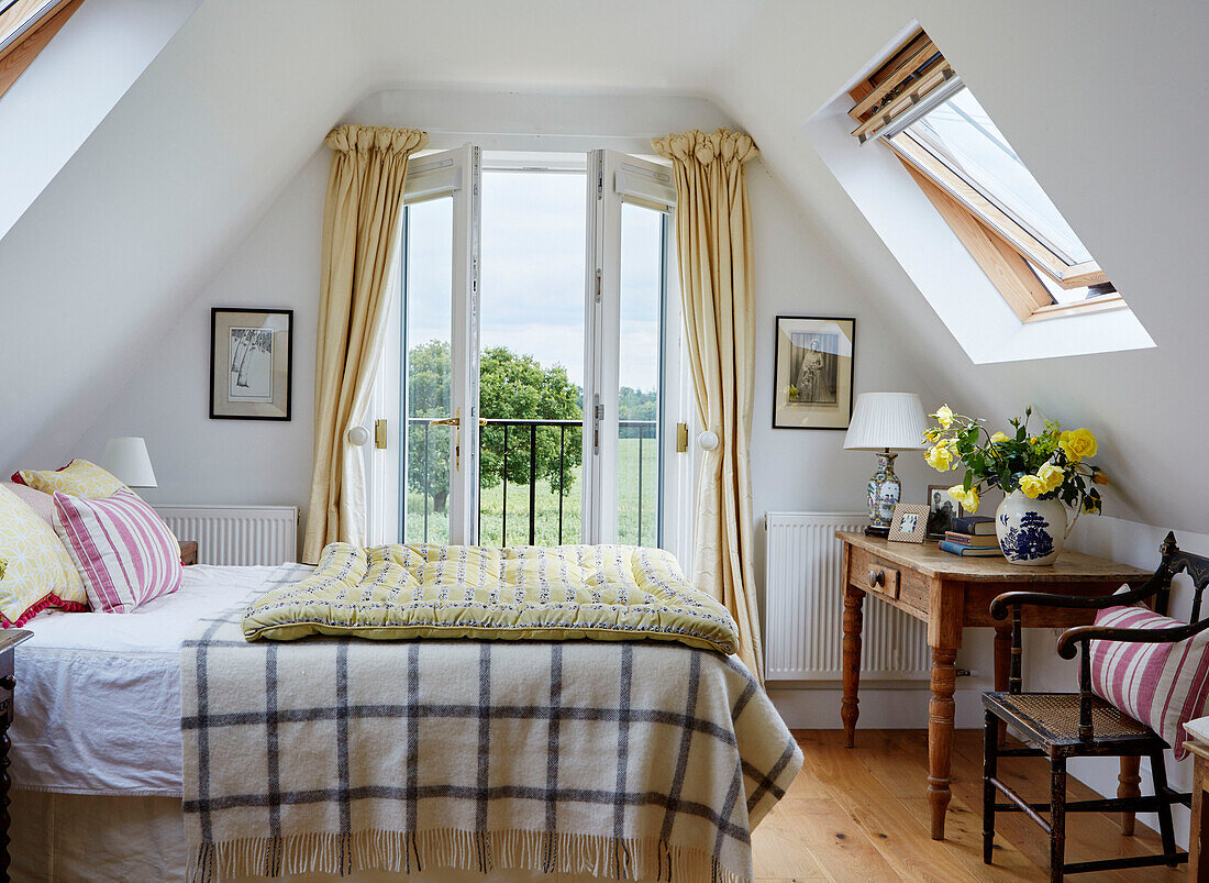 Gelbe Steppdecke auf einem Doppelbett mit offenen Türen und Blick auf die Landschaft von Oxfordshire, UK