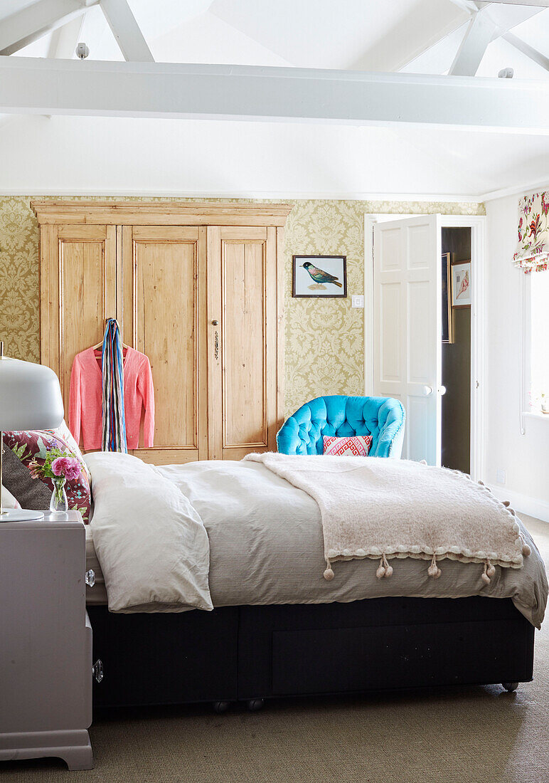 Doppelbett und hölzerner Kleiderschrank unter der Balkendecke in einem Haus in Deddington, Oxfordshire, UK