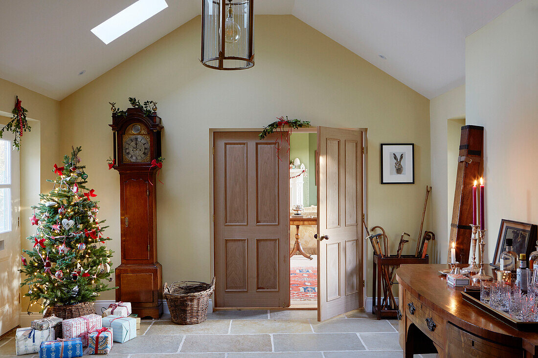 Weihnachtsbaum und Uhr in der Eingangshalle eines Bauernhauses in Northumberland, UK