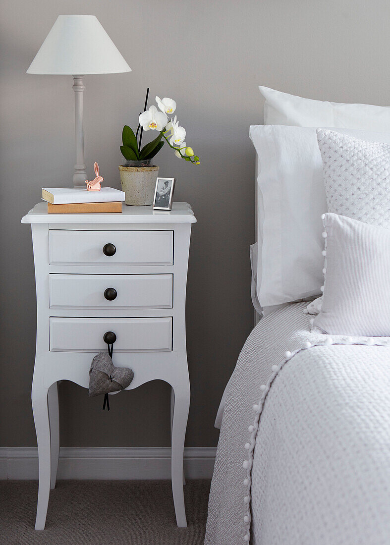 White drawers with orchid at bedside in North Yorkshire home, UK