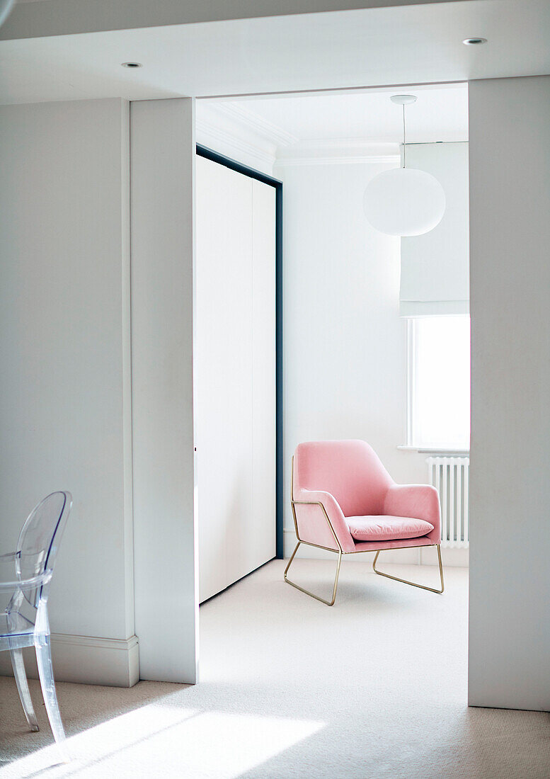 Sliding doors to dressing room with frame armchair in South East London home, UK