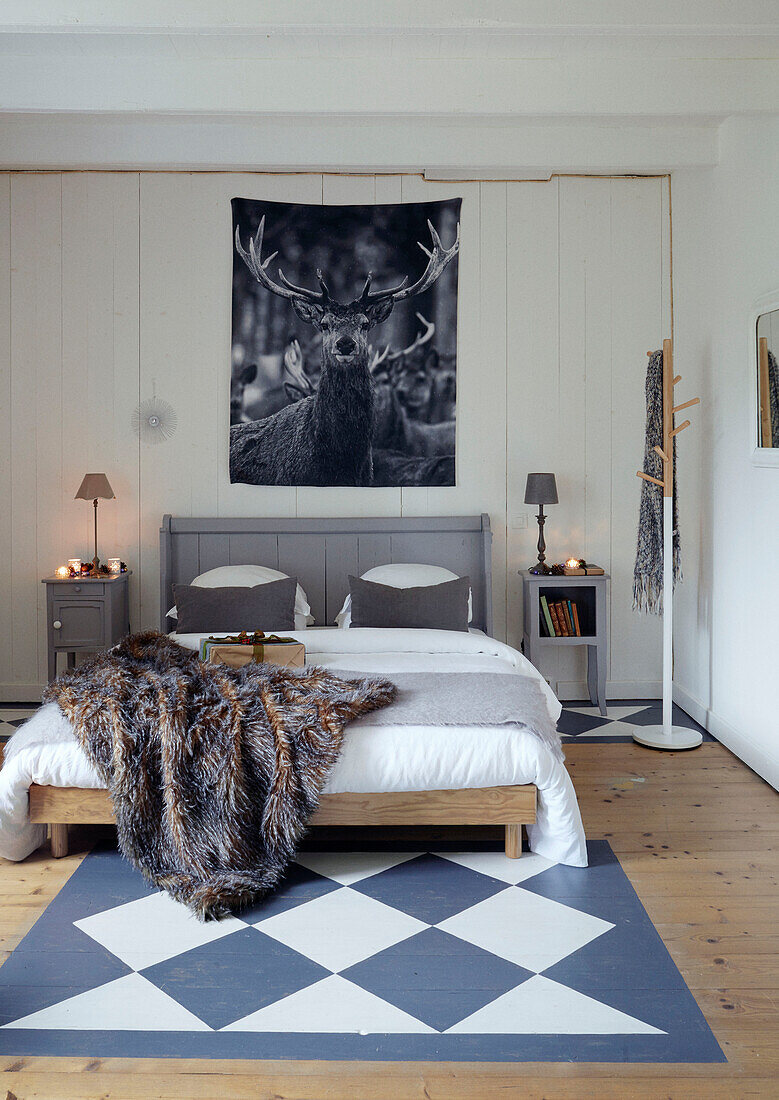 Fur throw on double bed with chequered floor paint in Brittany cottage, France