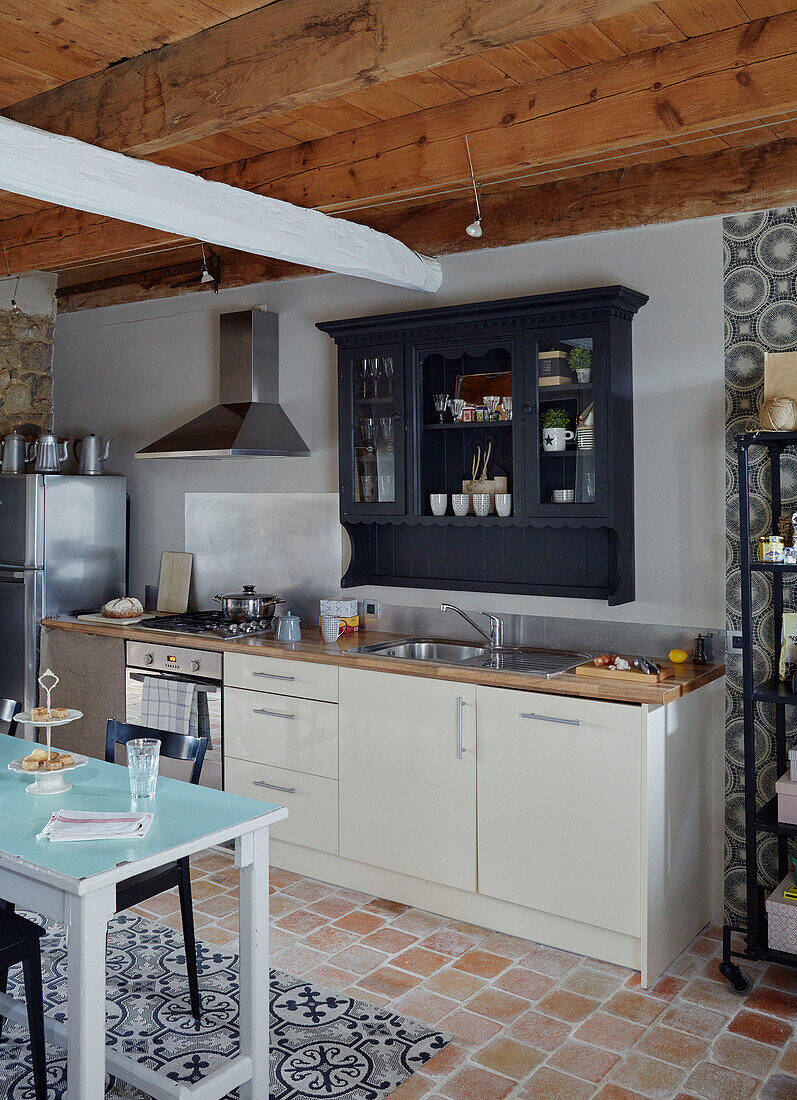 Kontrastierende Muster und Terrakottafliesen in einer Küche in der Bretagne, Frankreich